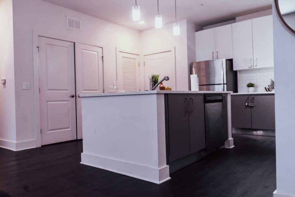 a kitchen with white cabinets and black floors