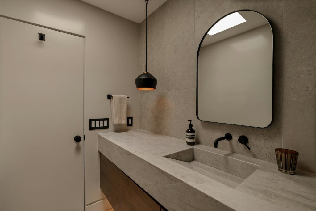 Modern bathroom with concrete sink and black faucet.