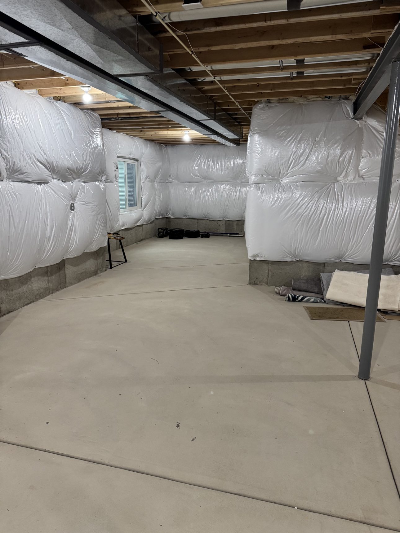 Unfinished basement before finishing — open ceiling joists, concrete floor, insulation