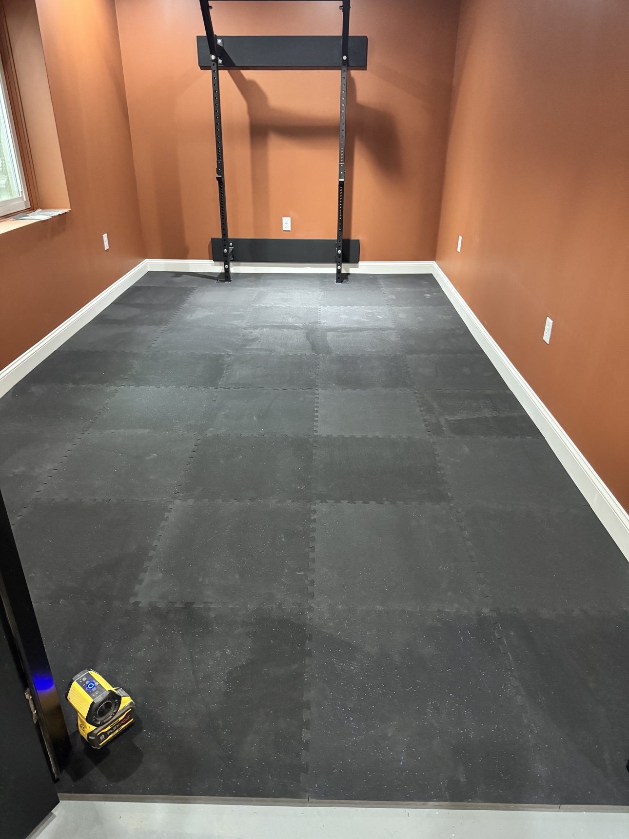Finished basement home gym with foam tile flooring and terracotta walls