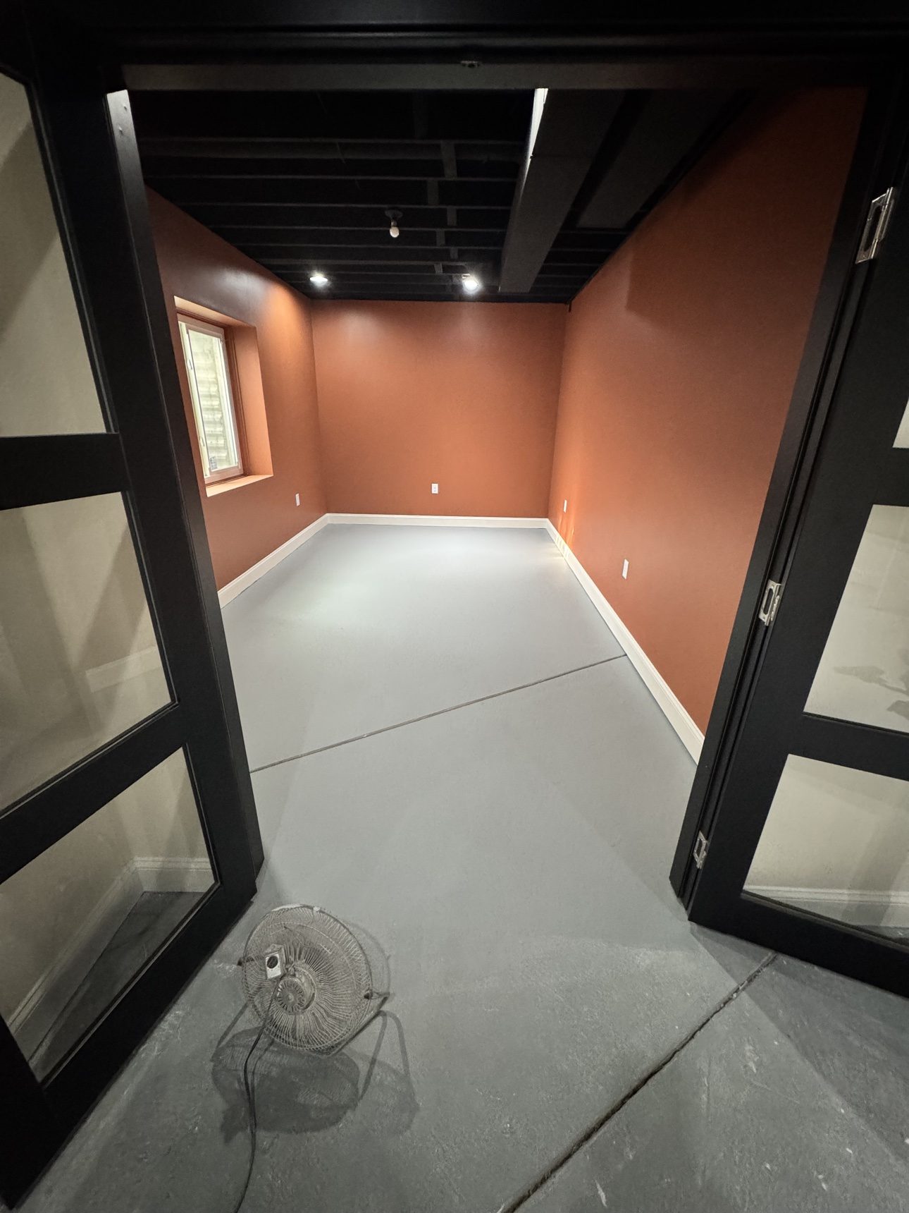 Finished basement family room interior with terracotta walls and black ceiling