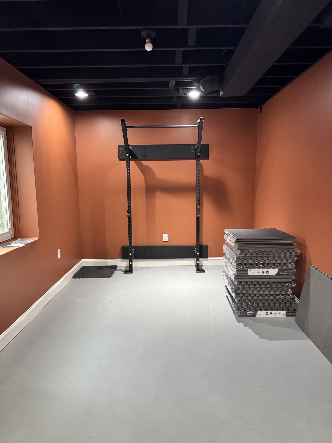 Basement home gym during installation with exercise rig and foam floor tiles